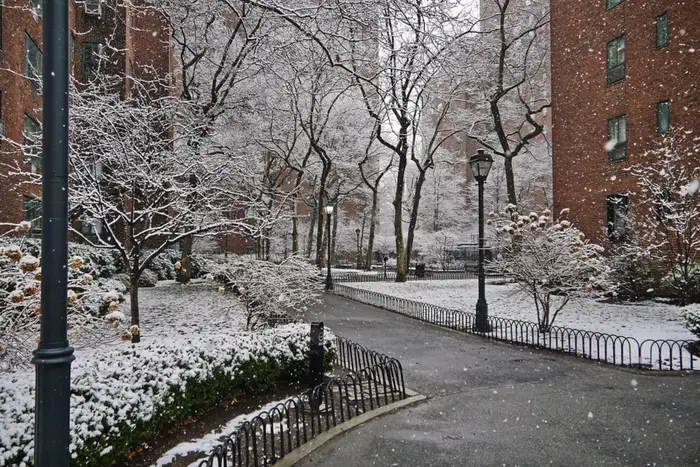 snow falls in an apartment complex courtyard